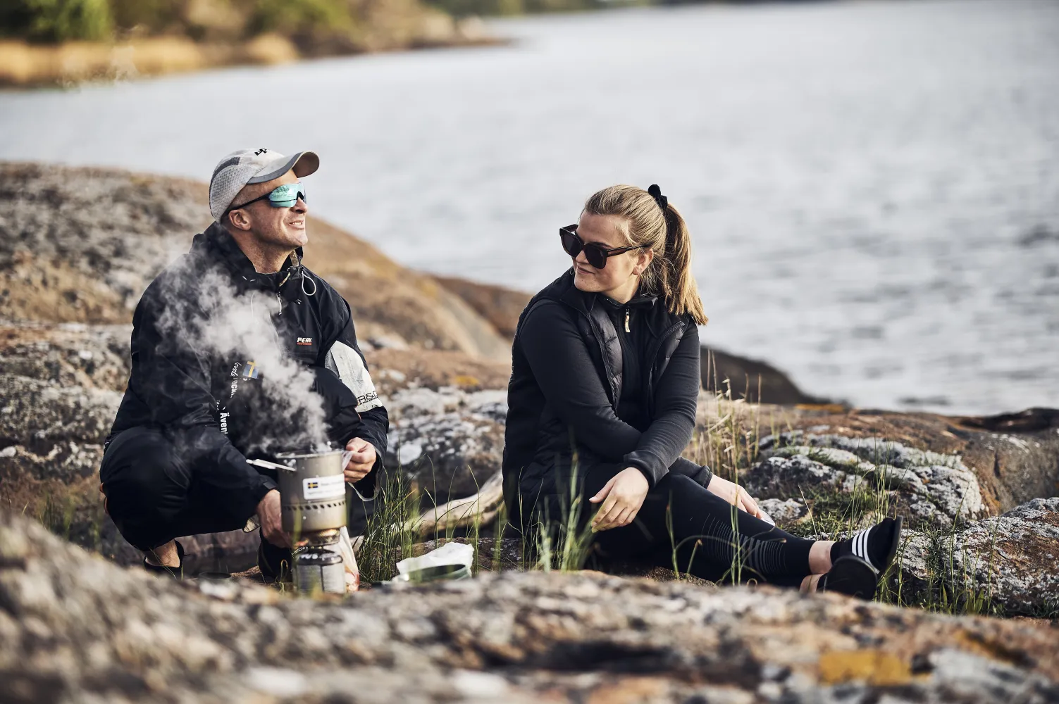 Två personer lagar mat bland klipporna i skärgården