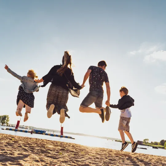 Hoppande familj på stranden